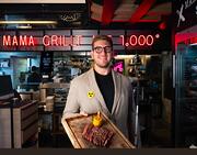 BSA Präsident Moritz Huth, Geschäftsführer von 'Mama & der Bulle 2' steht mit Schneidebrett und darauf platziert ein Steak, im Restaurant